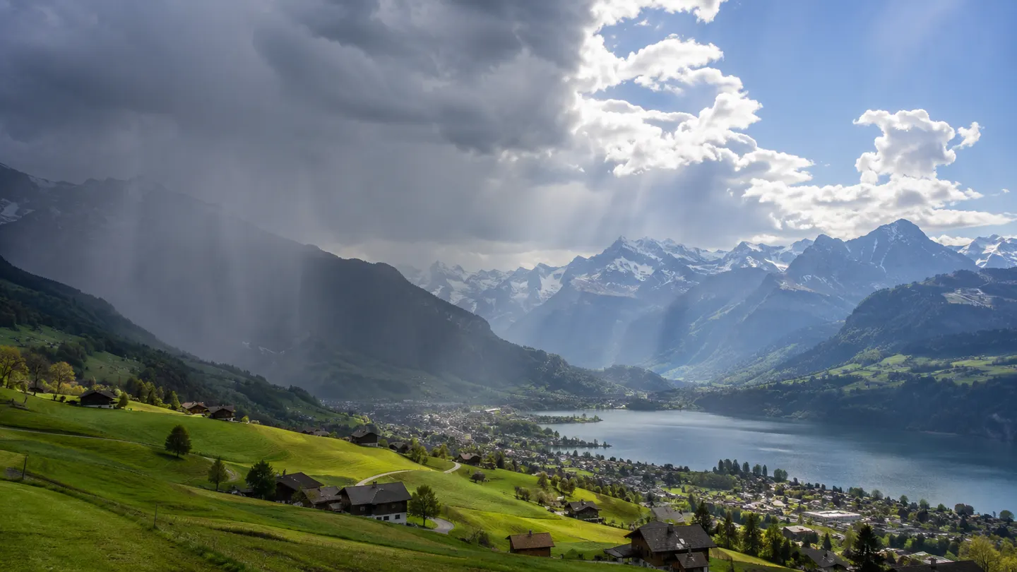 Österreichisches Alpental mit dunklen Regenwolken und sonnigen Auflockerungen