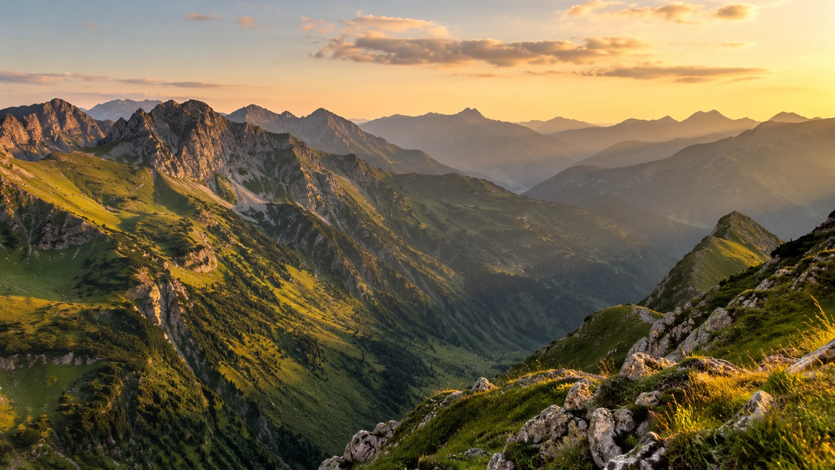 Schneefreie österreichische Alpenlandschaft mit grünen Hängen und felsigen Gipfeln im Abendlicht.