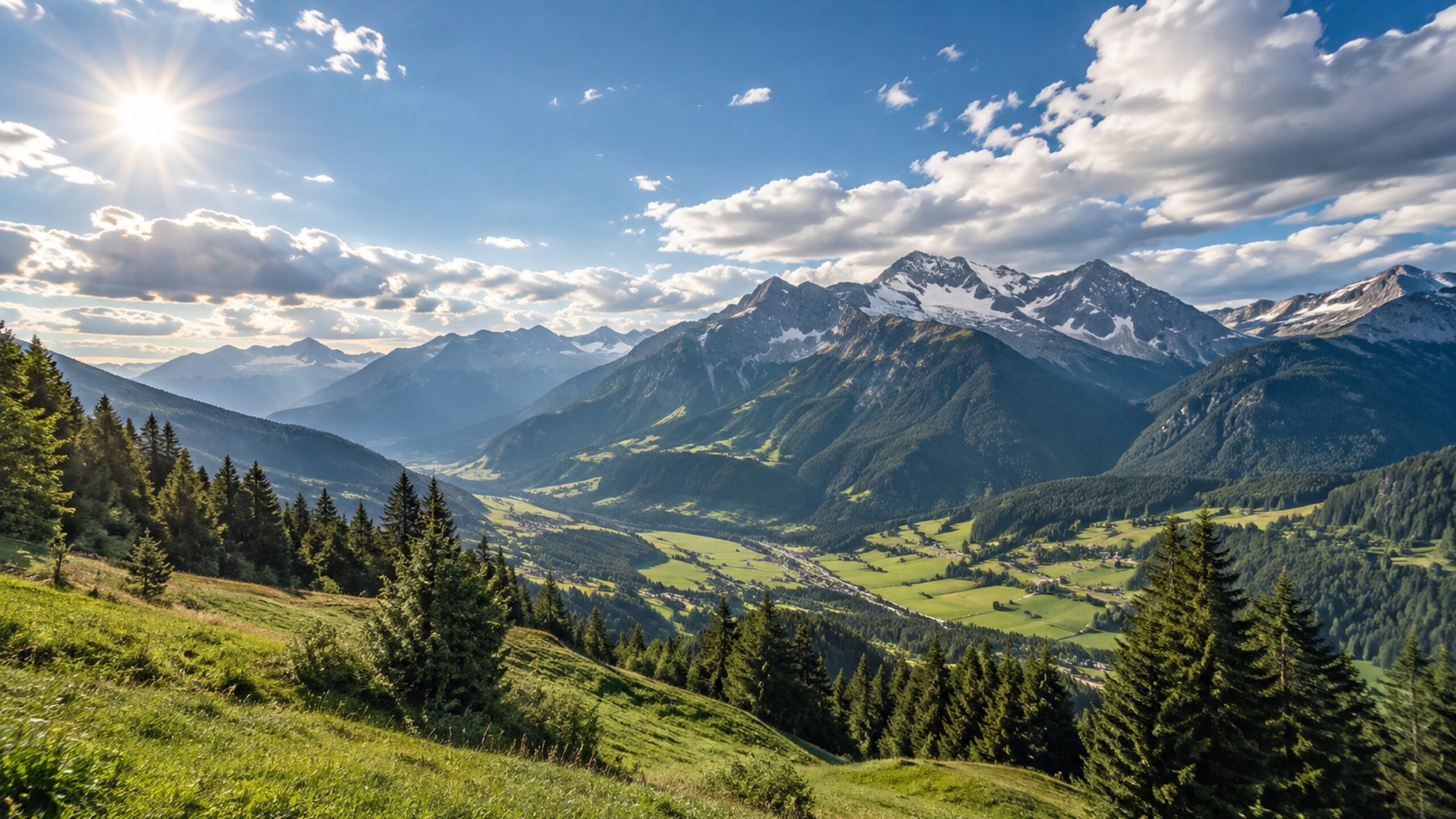 Sonniges österreichisches Alpental mit grünen Hängen und hohen Bergen unter locker bewölktem Himmel.
