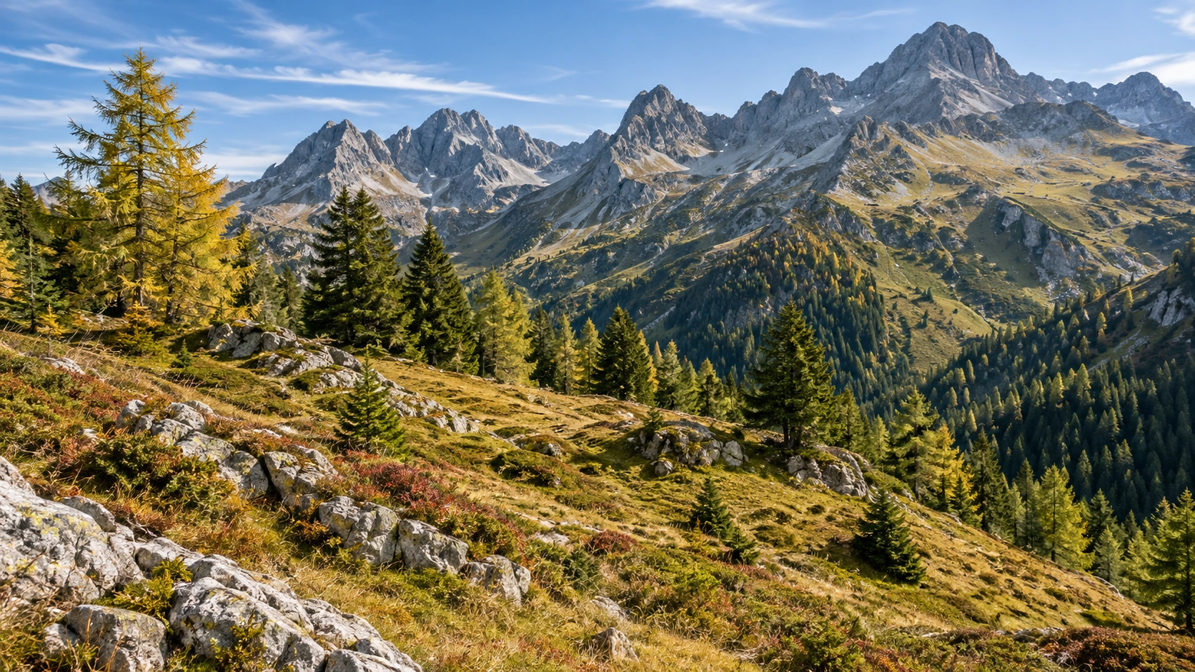 Schneefreie österreichische Alpenlandschaft mit Felsgipfeln, Lärchen, Wiesen und klarem Septemberlicht.
